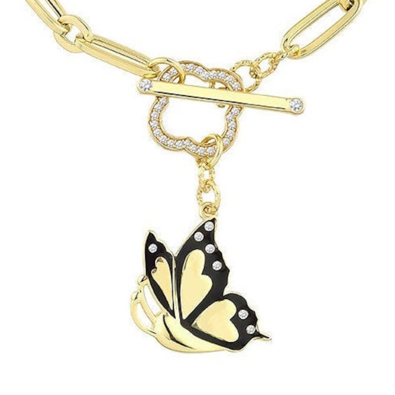 K&ouml;nnte beinhalten: Ein goldenes Kettenarmband mit einem herzf&ouml;rmigen Anh&auml;nger und einem schwarzen und goldenen Schmetterlingsanh&auml;nger. Der Schmetterling hat klare Strasssteine auf seinen Fl&uuml;geln.