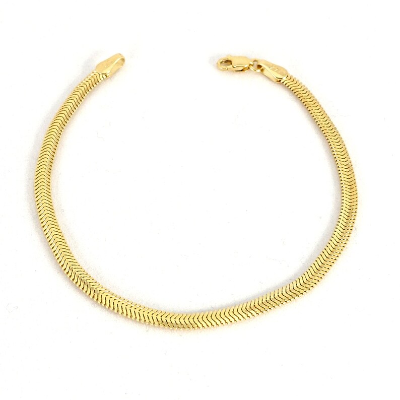 May include: A gold snake chain bracelet with a clasp closure.