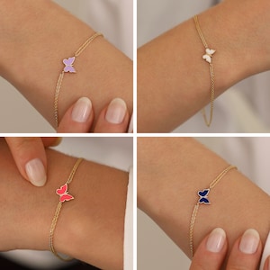 May include: Four gold chain bracelets with a butterfly charm. The butterflies are different colors: purple, white, pink, and blue.