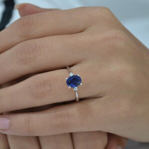 May include: A silver ring with a large oval blue sapphire and two smaller diamonds on either side.