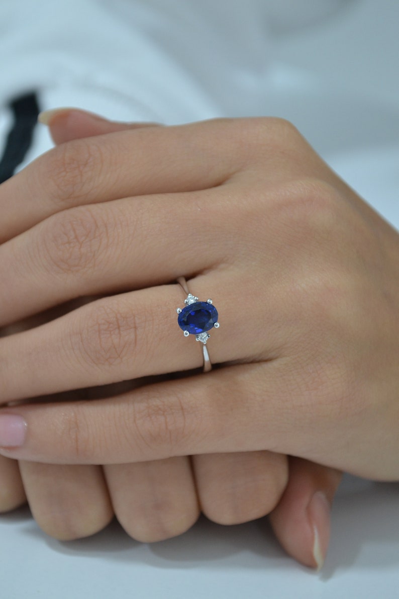 May include: A silver ring with a large oval blue sapphire and two smaller diamonds on either side.