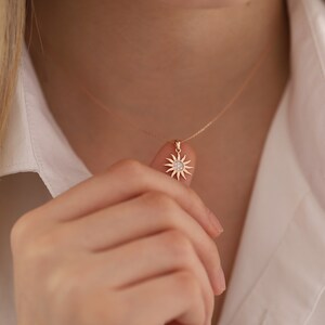 May include: A rose gold necklace with a sun pendant featuring a small round diamond in the centre.
