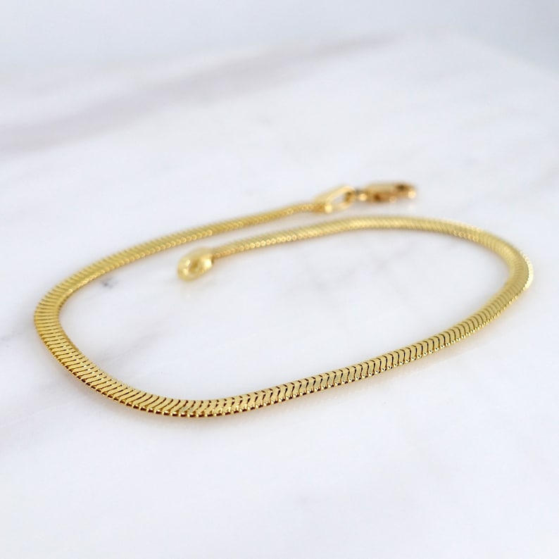 May include: A gold chain bracelet with a snake chain design.