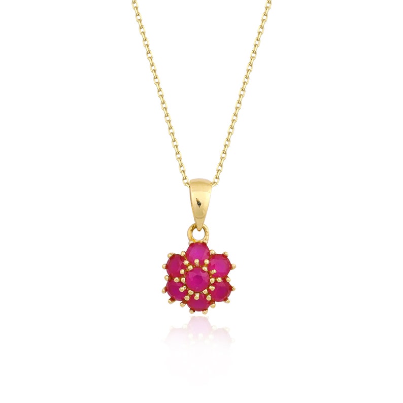 May include: A gold chain necklace with a pendant featuring a cluster of pink gemstones in a flower shape.