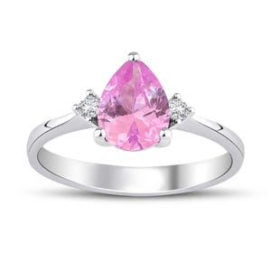 May include: A pear-shaped pink gemstone ring with two smaller diamond accents set in white gold.