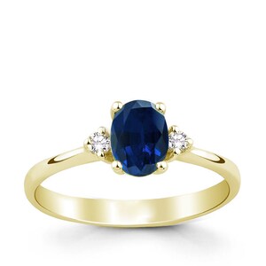 May include: A gold ring with a blue oval sapphire and two smaller diamonds on the sides.