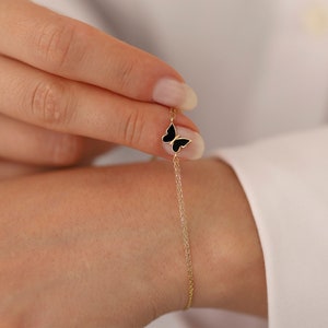 May include: A delicate gold chain bracelet with a black enamel butterfly charm.