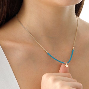 May include: A gold chain necklace with a turquoise bead strand and a small gold disc pendant.