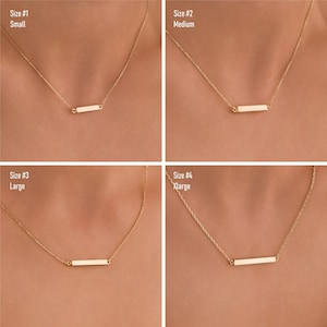May include: Four gold necklaces with a horizontal bar pendant. The necklaces are shown in four different sizes: small, medium, large, and extra large. The necklaces are on a model's neck.