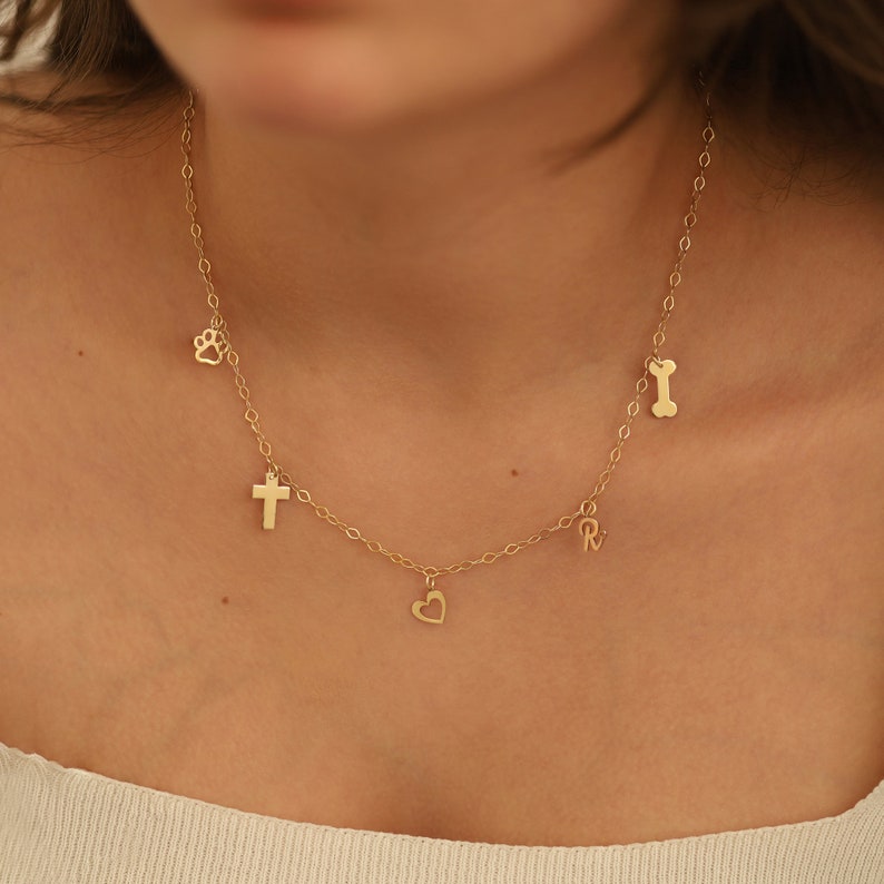 May include: A gold chain necklace with multiple charms, including a heart, cross, paw print, and bone.