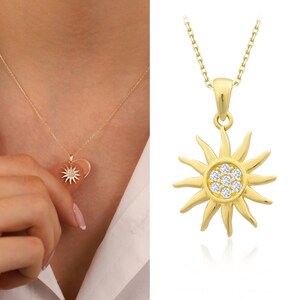 May include: A gold necklace with a sun pendant featuring clear cubic zirconia stones.