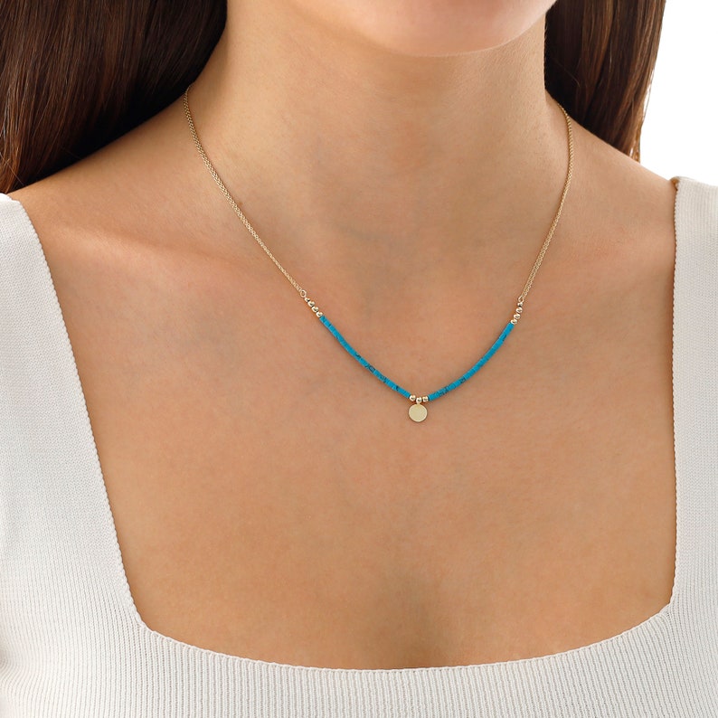 May include: A gold necklace with a turquoise beaded chain and a small gold disc pendant.