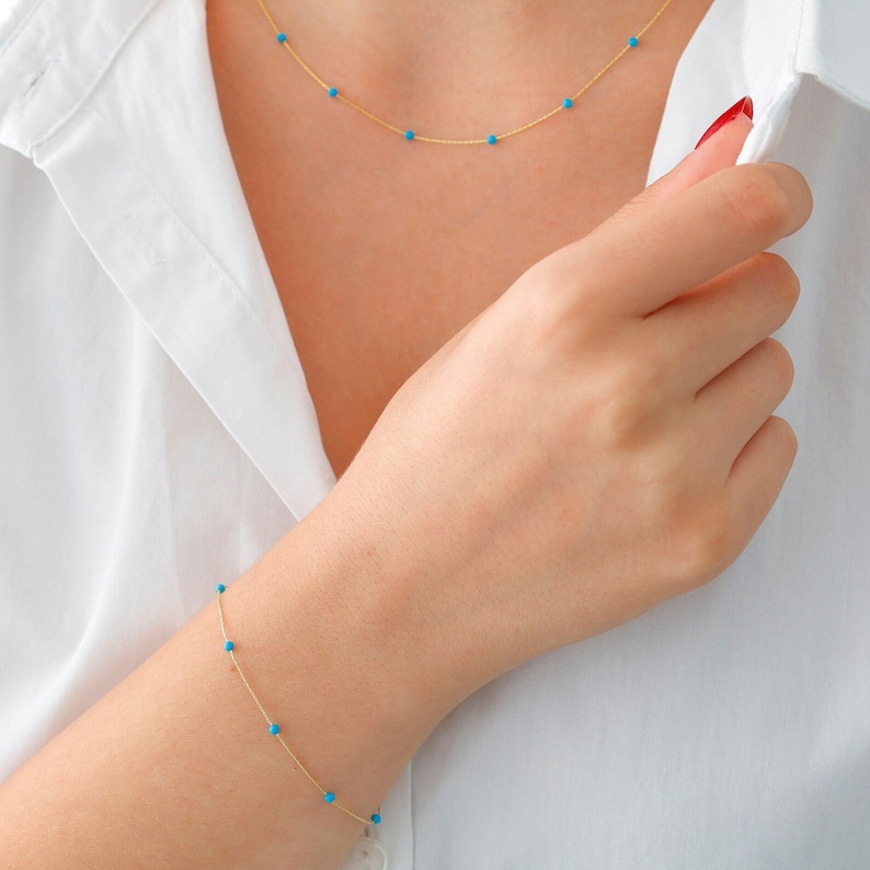 May include: A gold chain necklace and bracelet with small turquoise beads.