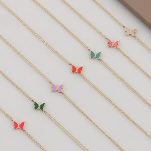 May include: Seven gold chain necklaces with colorful enamel butterfly charms. The butterflies are in shades of pink, red, green, blue, purple, and white.