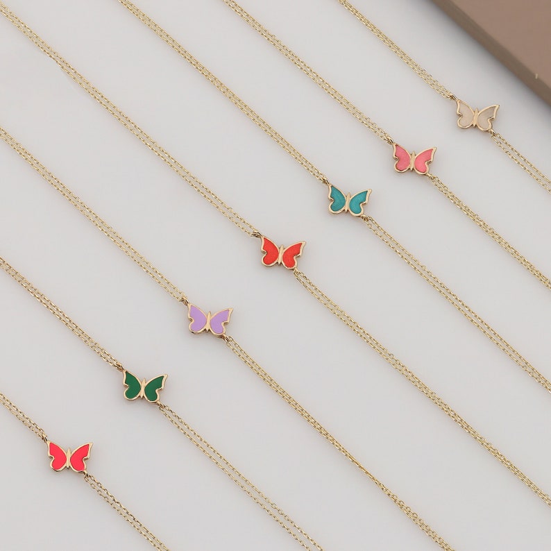 May include: Seven gold chain necklaces with colorful enamel butterfly charms. The butterflies are in shades of pink, red, green, blue, purple, and white.