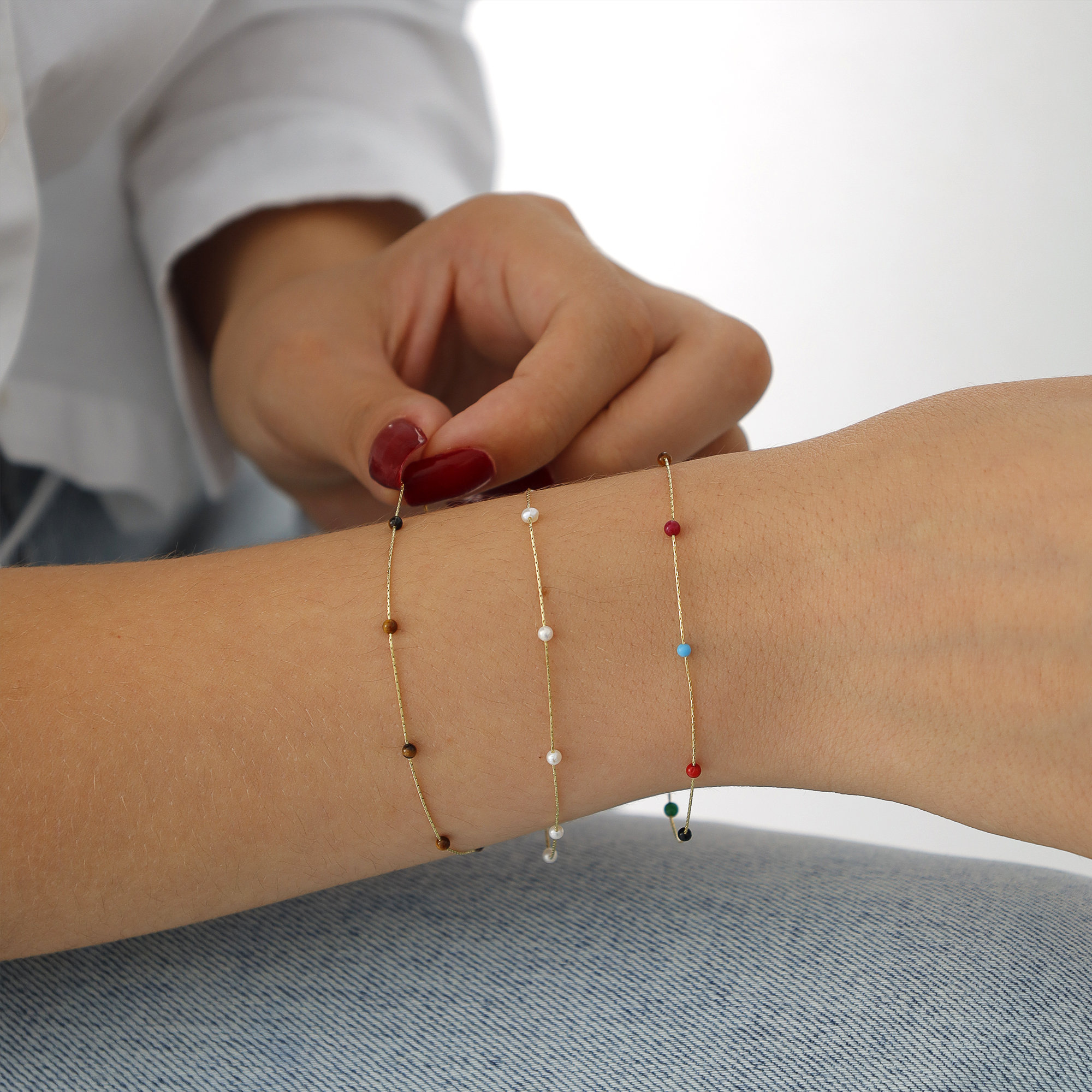 May include: Four gold chain bracelets with different colored beads. The bracelets feature black, white, red, and turquoise beads.