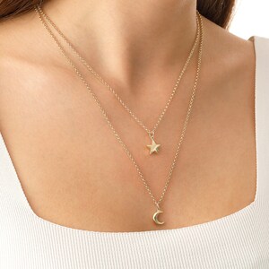May include: A gold chain necklace with a star and crescent moon pendant. The necklace is layered and features a delicate chain.