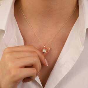 May include: A gold necklace with a heart-shaped pendant featuring a sun design with a small diamond in the centre.