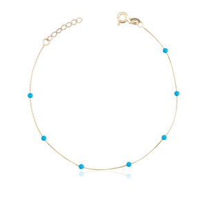 May include: A delicate gold chain anklet with small turquoise blue beads.