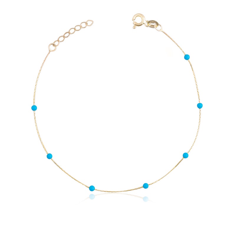 May include: A delicate gold chain anklet with small turquoise blue beads.