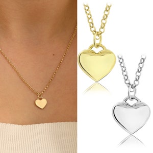 May include: Two gold heart necklaces, one with a gold heart pendant and the other with a silver heart pendant.