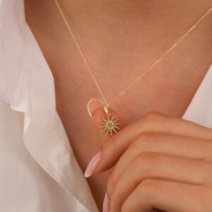 May include: A gold necklace featuring a sun pendant. The pendant is crafted from gold and has an intricate design.