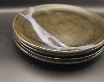May include: A stack of four ceramic plates. The plates are a dark olive green with a white and blue abstract design. The plates have a slightly textured surface and a simple, minimalist design.