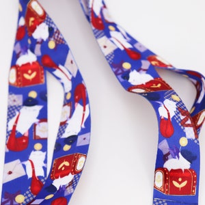 May include: A blue lanyard with a white cat and red mailbox pattern. The lanyard is made of a soft, durable material and is perfect for holding keys, badges, or other small items.