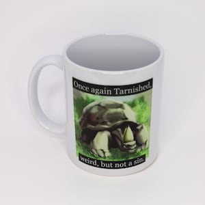 Puede incluir: Taza de cerámica blanca con un gráfico de una tortuga con el texto "Once again Tarnished. weird, but not a sin."