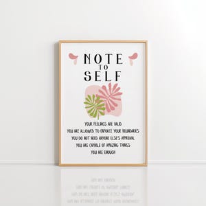 May include: A framed print with a pink and green floral design and the text "NOTE TO SELF" in black. The text below the floral design reads "YOUR FEELINGS ARE VALID YOU ARE ALLOWED TO ENFORCE YOUR BOUNDARIES YOU DO NOT NEED ANYONE ELSE'S APPROVAL YOU ARE CAPABLE OF AMAZING THINGS YOU ARE ENOUGH".