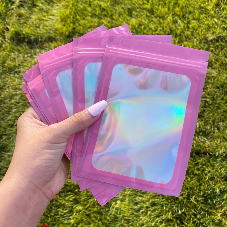 K&ouml;nnte beinhalten: Ein Stapel rosa, schimmernde, wiederverschlie&szlig;bare Plastikt&uuml;ten mit einem transparenten Fenster. Die Beutel sind perfekt zum Verpacken kleiner Gegenst&auml;nde.