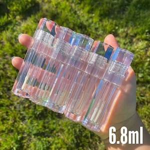 May include: Six clear plastic tubes with a silver cap, each containing a clear liquid. The tubes are arranged in a row and are held in a hand. The text "6.8ml" is visible in the bottom right corner of the image.