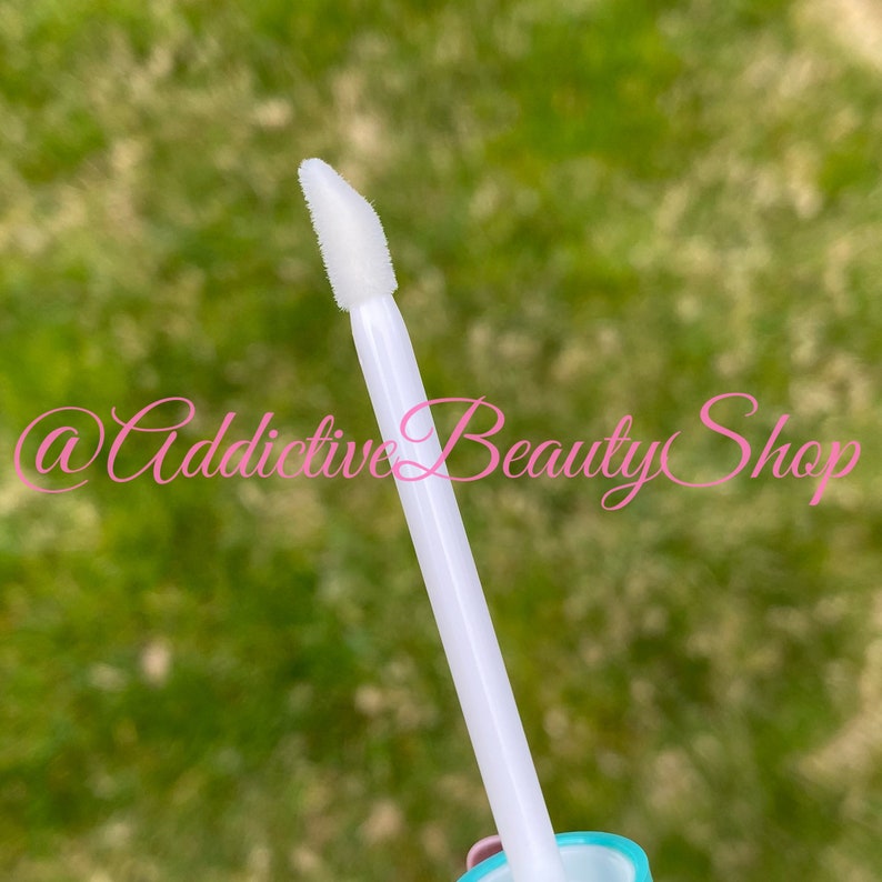 Puede incluir: Primer plano de una varita aplicadora blanca con una punta puntiaguda. La varita se utiliza para aplicar brillo de labios u otros cosm&eacute;ticos l&iacute;quidos.