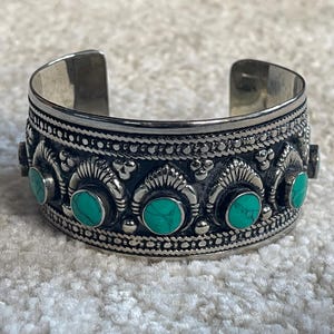 Può includere: Braccialetto rigido in argento con un design elaborato e pietre turchesi.