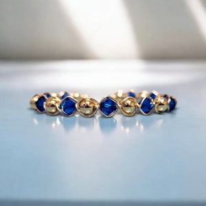 May include: A gold and blue beaded bracelet with alternating gold beads and blue faceted beads.