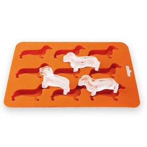 May include: Orange silicone ice cube tray with dachshund-shaped moulds. Three dachshund-shaped ice cubes are frozen in the tray.