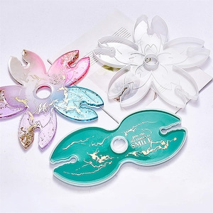 Peut inclure: Trois moules en silicone différents pour l'artisanat de la résine. Les moules sont en forme de fleur, de double boucle et de fleur avec un trou central. Les moules sont transparents et montrent les détails du design.