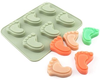 May include: A green silicone mold with eight baby foot shapes. The mold is filled with colorful, handmade soaps in shades of green, orange, and pink.