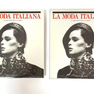 Könnte beinhalten: Zwei identische Bücher mit dem Titel LA MODA ITALIANA mit einem schwarz-weißen Coverfoto einer Person, die einen Hut mit Schleier und einen Schal mit Leopardenmuster trägt. Der Text LA MODA ITALIANA erscheint in Rot auf dem weißen Einband.