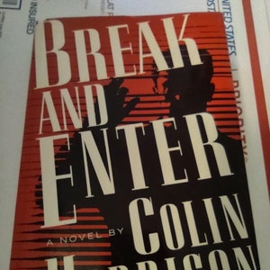 May include: A red and black paperback book with the title "Break and Enter" and the author's name "Colin Harrison" in white text. The book cover features a silhouette of a person's head and shoulders.