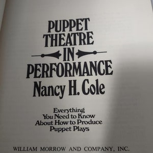 May include: A book titled "Puppet Theatre in Performance" by Nancy H. Cole. The book cover is white with black text and a black illustration of a puppet theatre stage. The subtitle is "Everything You Need to Know About How to Produce Puppet Plays". The book was published by William Morrow and Company, Inc. in 1978.