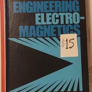 May include: A textbook titled "Engineering Electromagnetics" by Hayt, Third Edition. The cover is black with blue text and a blue geometric design. A white sticker with the price $15 is attached to the book.