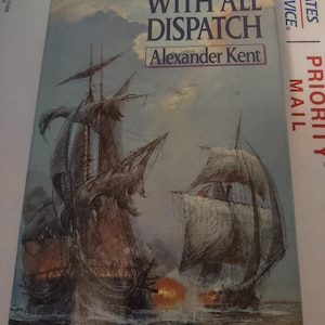 May include: A book cover with a painting of two ships at sea. The title of the book is "With All Dispatch" by Alexander Kent.