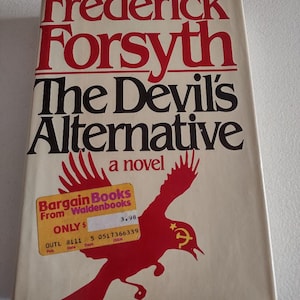 May include: A paperback book cover with a red bird flying with a hammer and sickle symbol on its wing. The book title is "The Devil's Alternative" by Frederick Forsyth. The cover also includes a sticker that says "Bargain Books from Waldenbooks" with a price of $3.98.