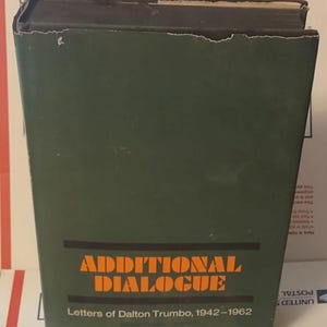 May include: A vintage book with a dark green cover. The title "ADDITIONAL DIALOGUE" is printed in orange block letters, with the subtitle "Letters of Dalton Trumbo, 1942-1962" below. The book shows signs of wear.