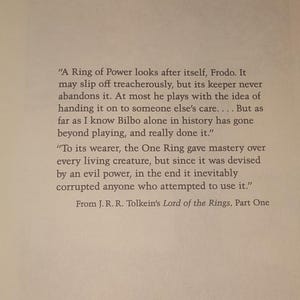 K&ouml;nnte beinhalten: Ein gedruckter Auszug aus J.R.R. Tolkiens Der Herr der Ringe, Teil eins, mit schwarzem Text auf hellem Hintergrund. Die Passage er&ouml;rtert den Einen Ring, seine Macht und den korrumpierenden Einfluss auf diejenigen, die ihn benutzen.