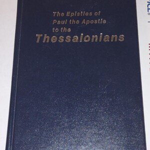 May include: A dark blue hardcover book with the title "The Epistles of Paul the Apostle to the Thessalonians" in gold lettering.