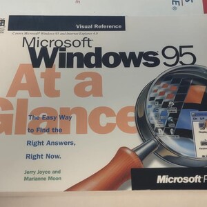 May include: A book cover with a magnifying glass showing a computer screen with the text "Control Panel" on it. The book cover is white with blue and black text that reads "Microsoft Windows 95 At a Glance The Easy Way to Find the Right Answers, Right Now. Jerry Joyce and Marianne Moon Microsoft Press".