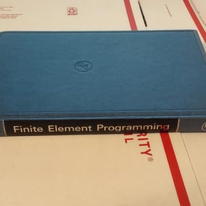 May include: A teal-colored book titled "Finite Element Programming" with the author's name, Hinton Owen, visible on the spine. The book has a dark band with white text and a logo on the cover.
