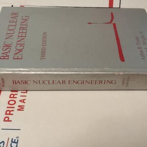 Puede incluir: Un libro gris claro titulado "Basic Nuclear Engineering, Third Edition". El t&iacute;tulo es rojo y los autores son Arthur R. Foster y Robert L. Wright, Jr. El libro est&aacute; sobre una superficie blanca y roja.